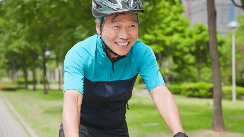 A man riding a bike on a path through a lush green park.