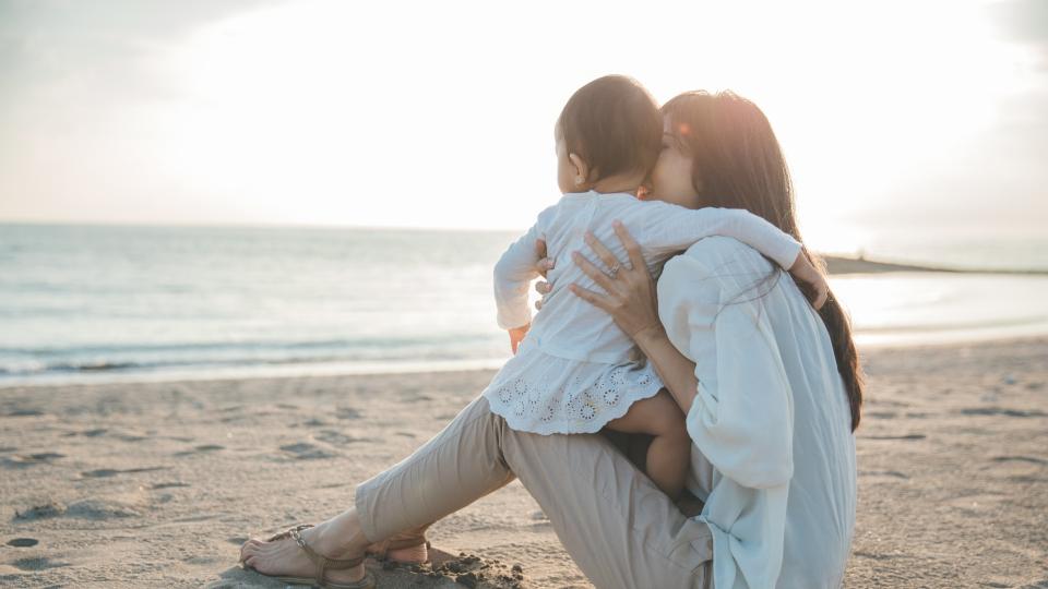 A woman and her child enjoying a peaceful moment on the beach, surrounded by the beauty of nature.