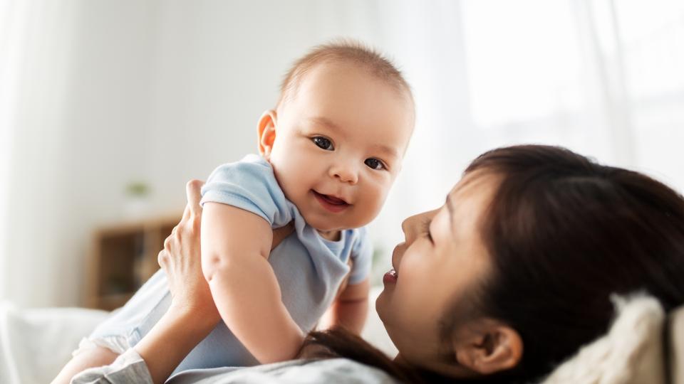 A woman cradling a baby on a couch.