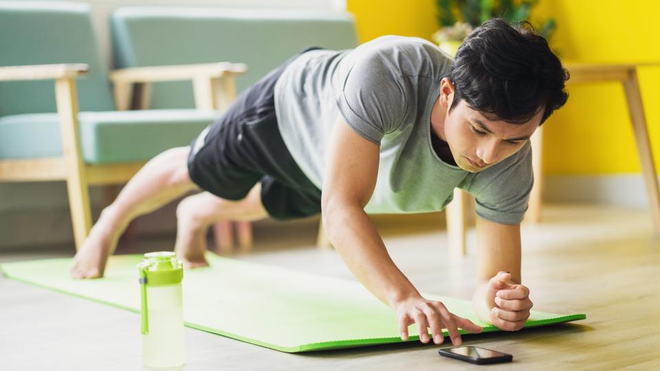 A man doing push ups on a yoga mat.