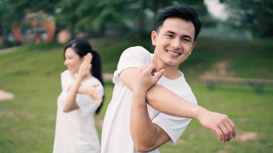 A man and woman stretching outdoors, enjoying a healthy exercise routine together.