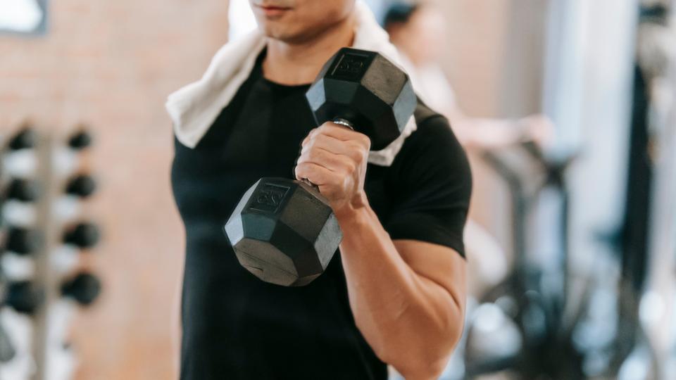 Fitness enthusiast working out with a dumbbell in a gym setting.