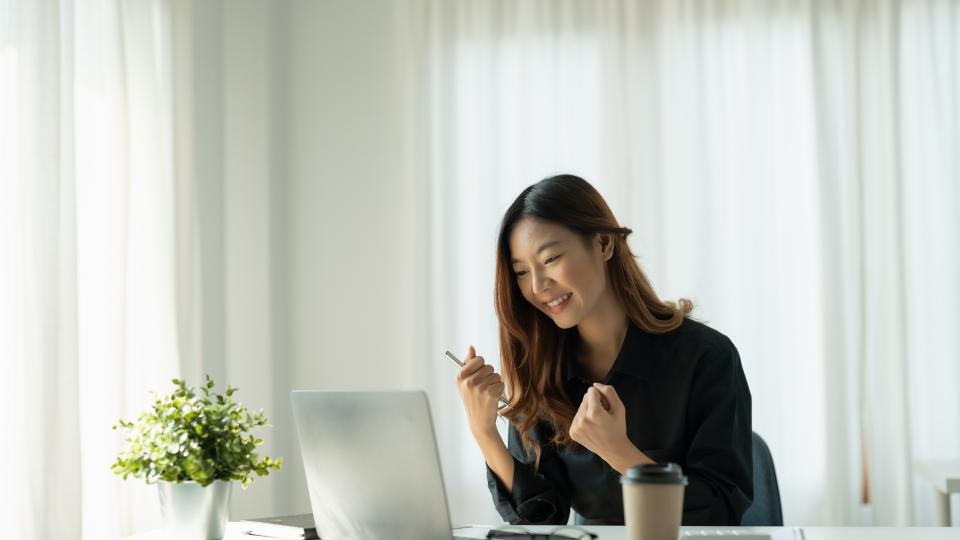 A woman sitting at a desk with a laptop and a cup of coffee.