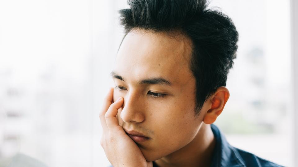 A man examining his hand on his face, deep in thought.