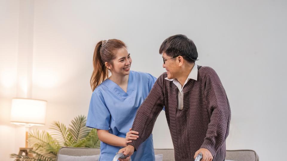 Man and woman using walker in living room.