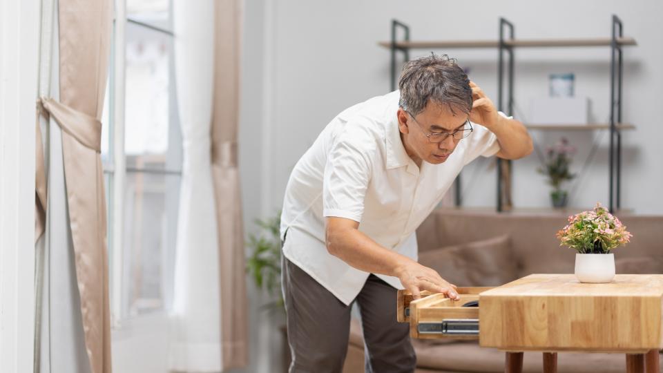 A man stands before a table, gazing at a wooden box placed on it.