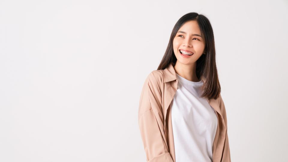 Smiling woman looking at camera on white background.