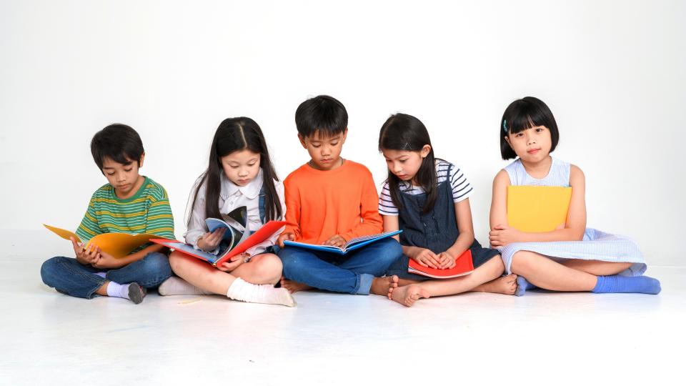 Children sitting on floor, engrossed in books. Nurturing Self-Esteem in Children.