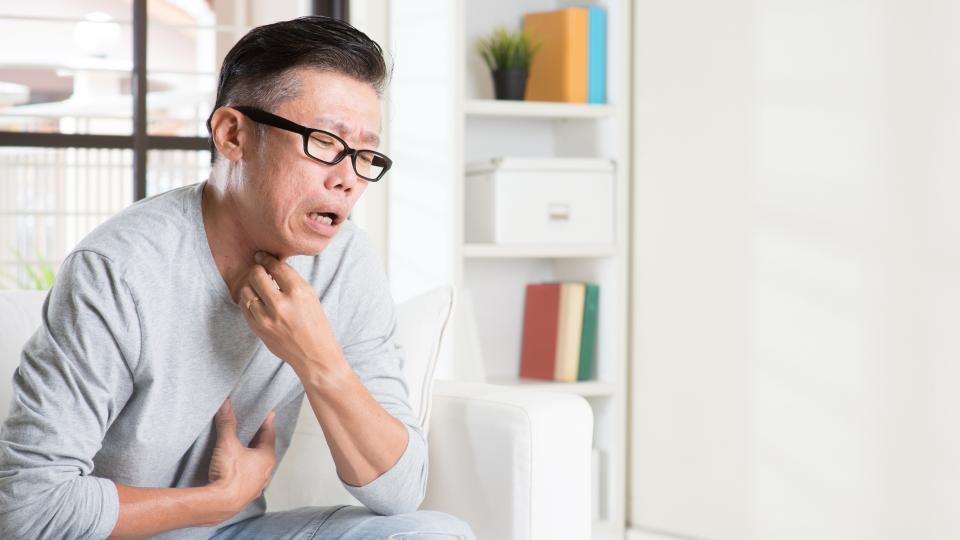 A man sitting on a couch, looking relaxed with his hands resting on his chest.