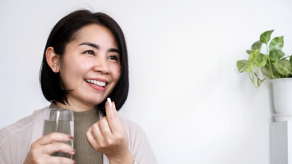 A woman smiling and holding a glass of water.