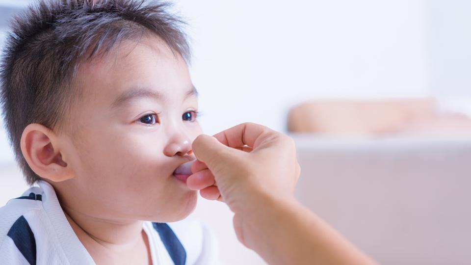 Parent lovingly feeding child with a spoon.