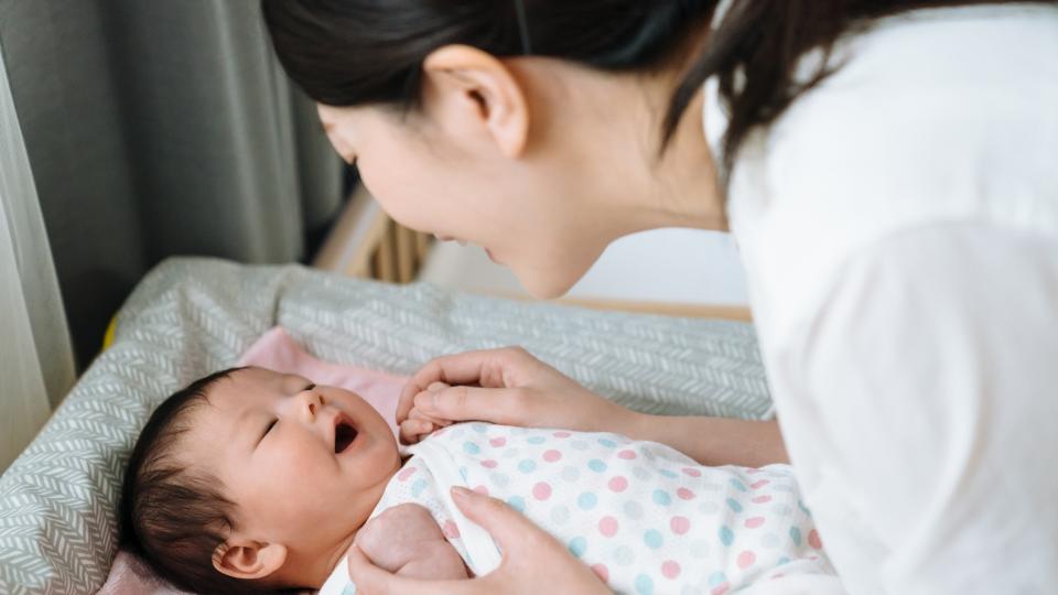 A woman joyfully cradles a baby in her arms, radiating happiness.