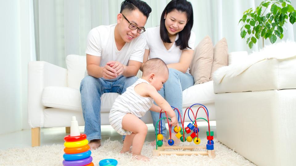 A family joyfully playing with their baby on a white carpet, creating precious memories together.