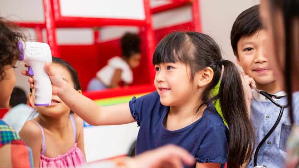 A child with a thermometer surrounded by other children, ready for some fun and games!