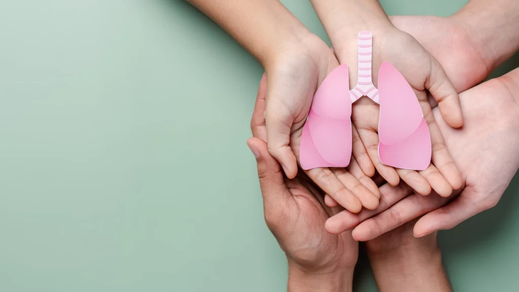 Hands holding a pink paper lung, symbolizing care for respiratory health.