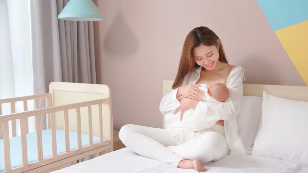 Breastfeeding as a Working Mother - A mother nurturing her baby by breastfeeding in a cozy bed.