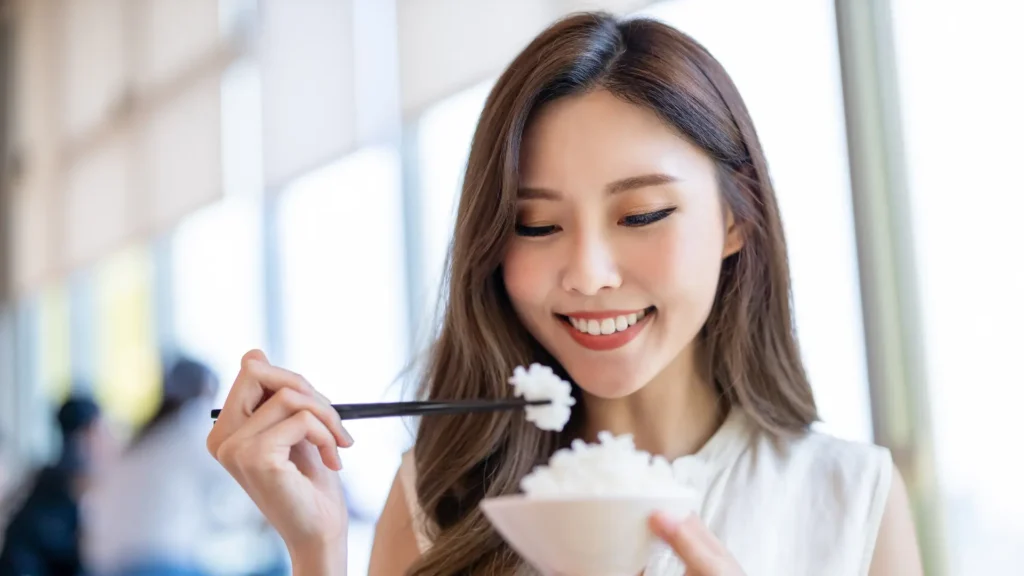 A woman enjoying a delicious meal of rice with chopsticks, savoring every bite with grace and skill. Diet or Exercise
