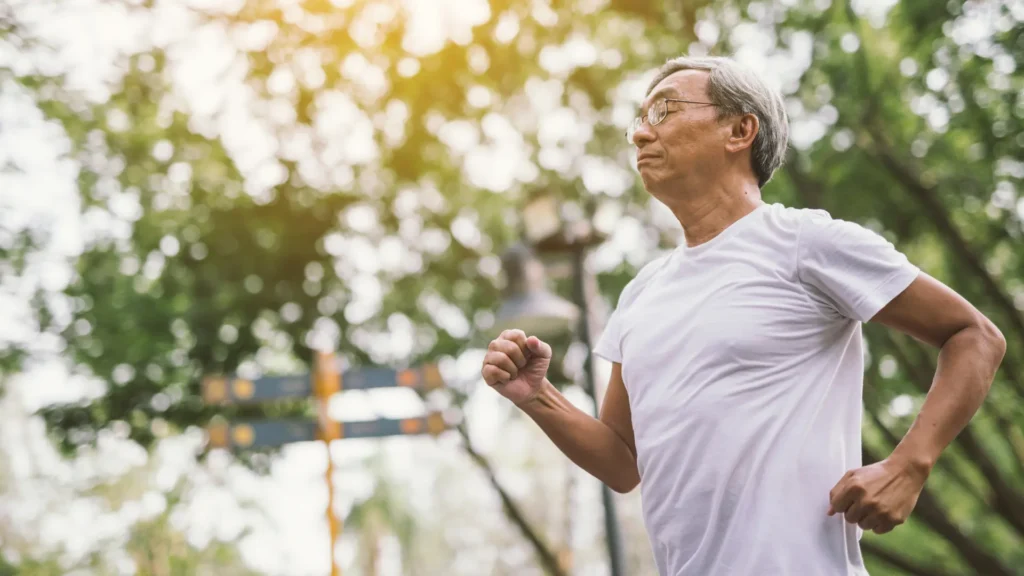 An elderly man jogging in a serene park, enjoying his exercise routine amidst nature's beauty.
