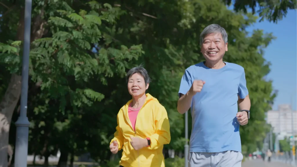 An older couple enjoying a jog together in the park, maintaining their active and healthy lifestyle.