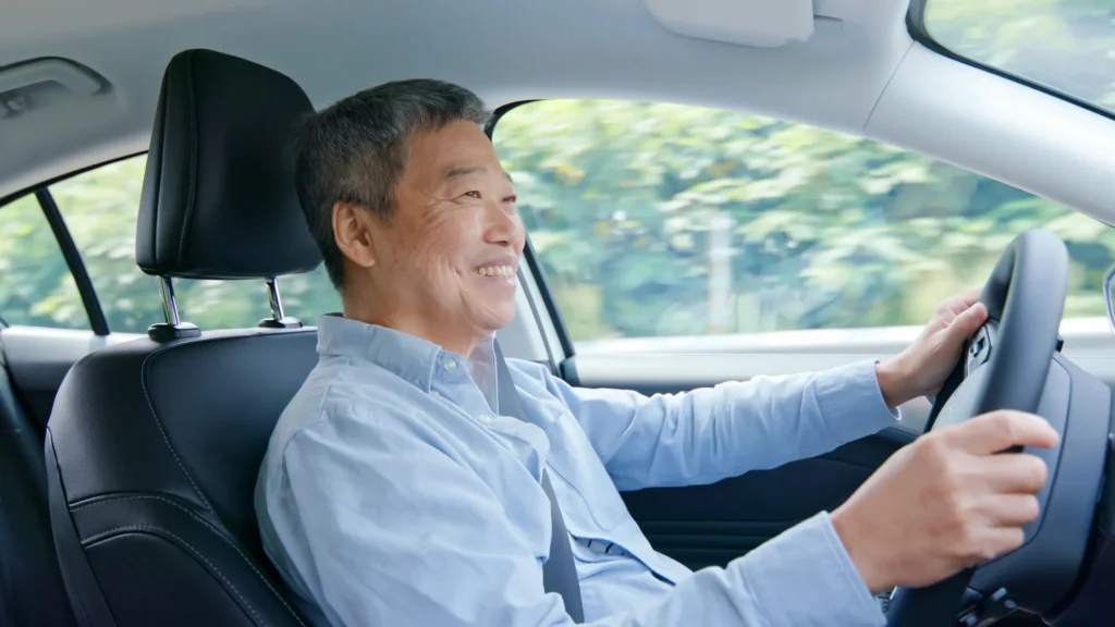 An elderly man confidently driving a car, displaying experience and skill behind the wheel.