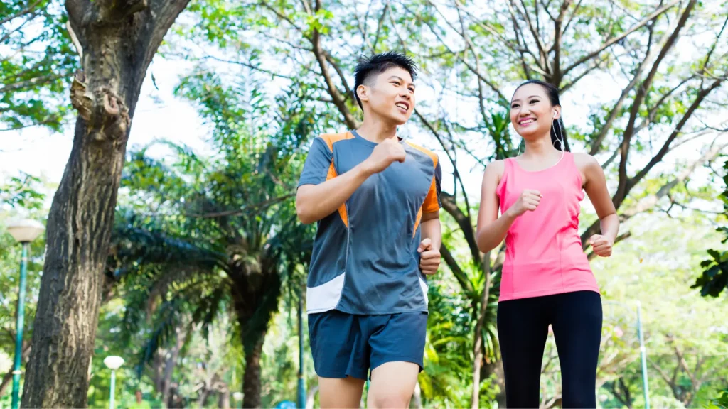 An Asian couple enjoying a jog in the park, staying fit and active together.