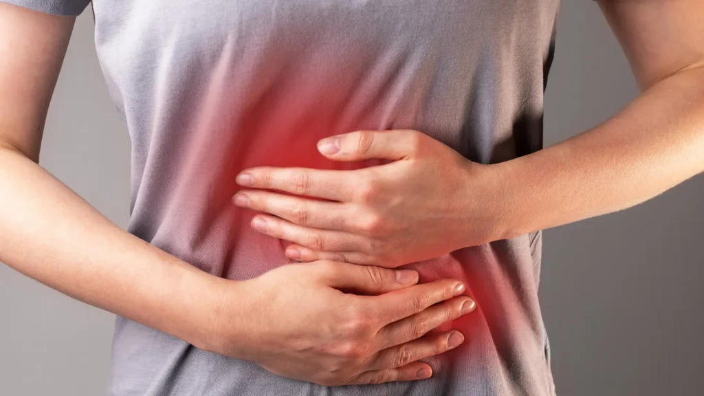A person holding their stomach in discomfort, possibly experiencing stomach pain.