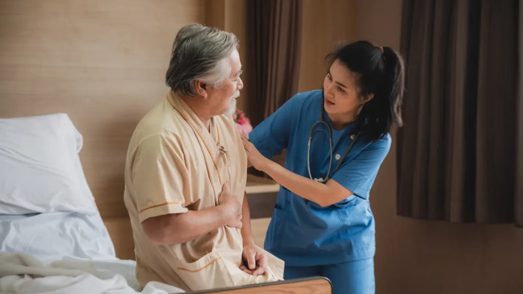 A caring nurse assisting an elderly man in bed, providing compassionate care and support.