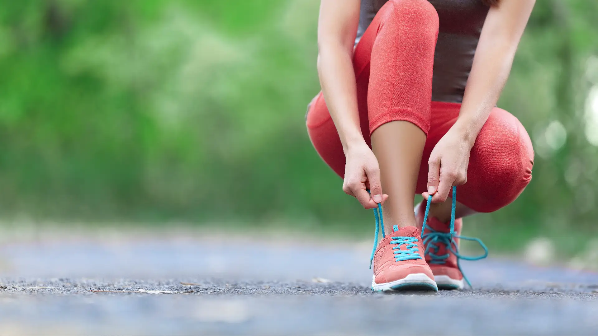 A woman tying her shoes on a road.