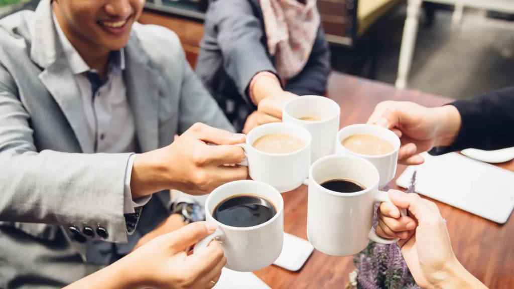 Business professionals raising coffee cups in celebration.