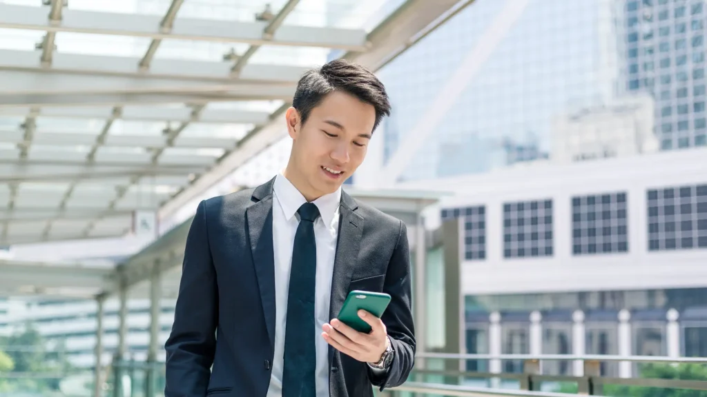 Businessman in suit using smartphone on city street.