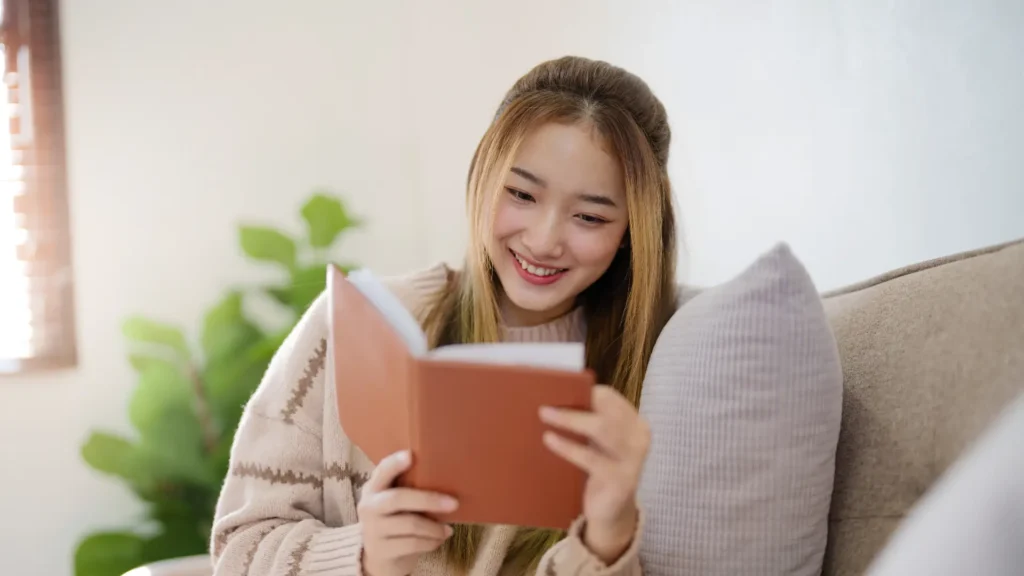 A woman happily reading a book with a smile on her face.
