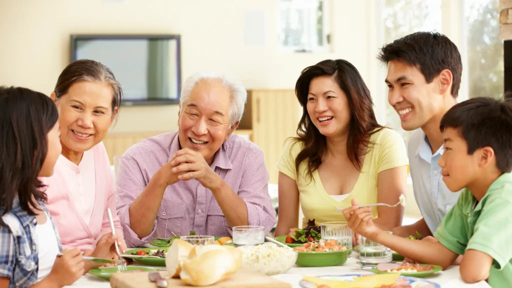 A happy family of four enjoying a meal together at the dinner table. Healthy Ageing Tips