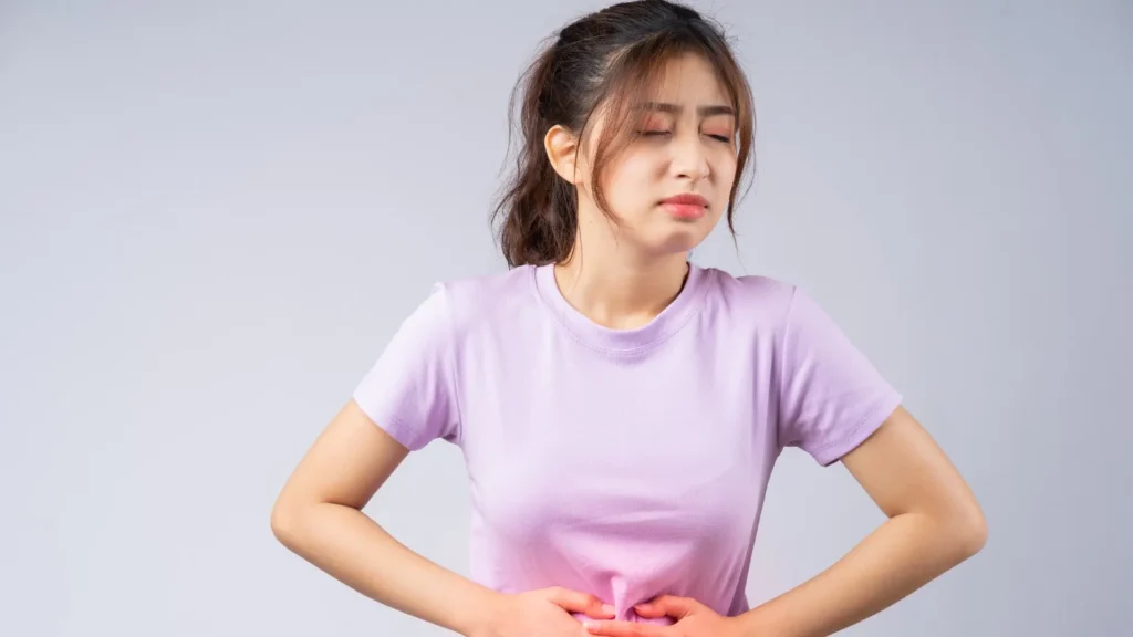 A woman holding her stomach in pain on white background.