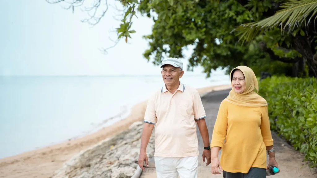 An elderly couple strolling on the beach, hand in hand, enjoying a peaceful and serene moment together.