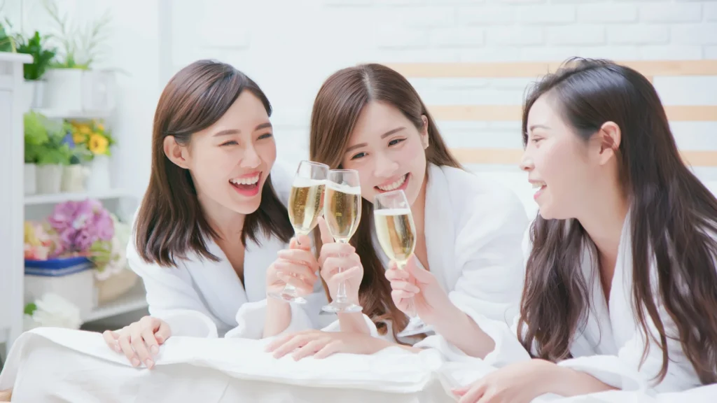 Three friends in bathrobes enjoying champagne together.