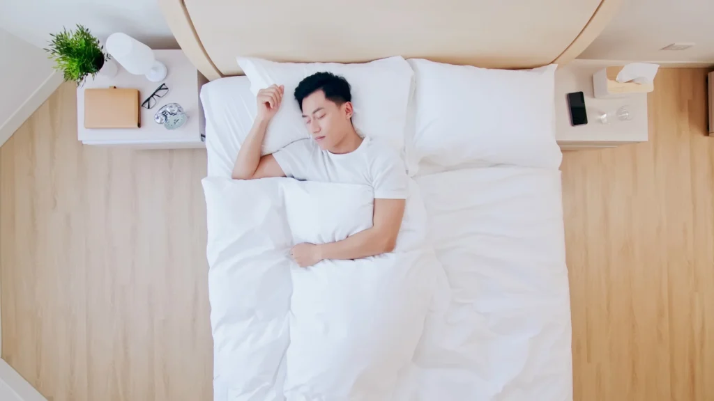 A man peacefully sleeping in bed with a white pillow.