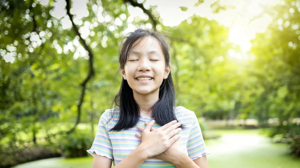A young girl happily smiling with her hands clasped together. Stress