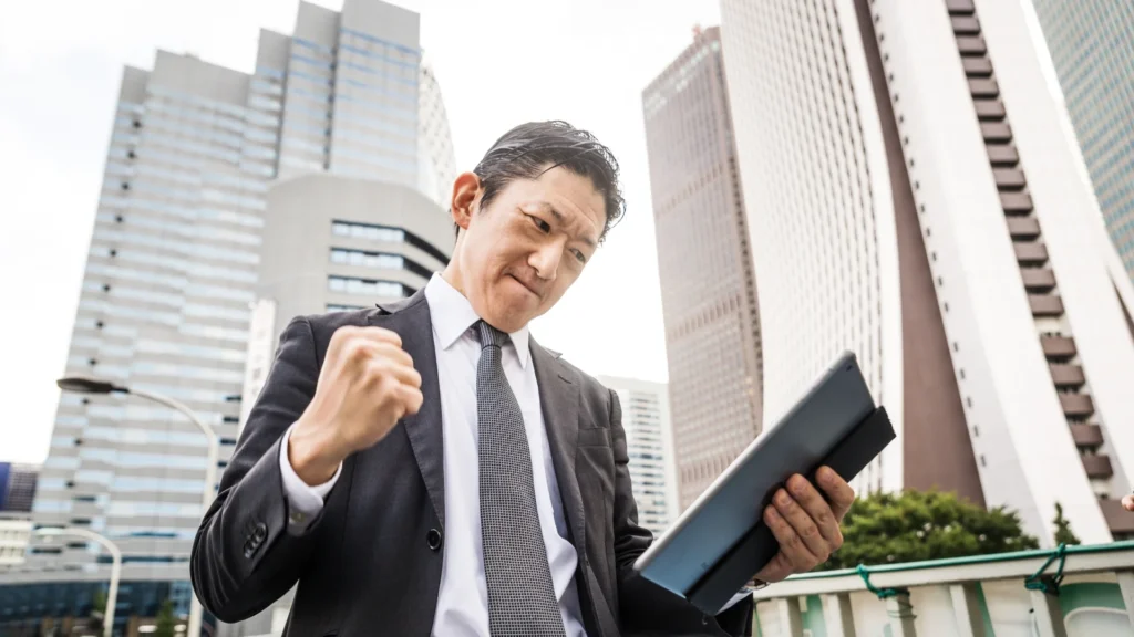 A businessman confidently holds a tablet computer while standing in a bustling city.