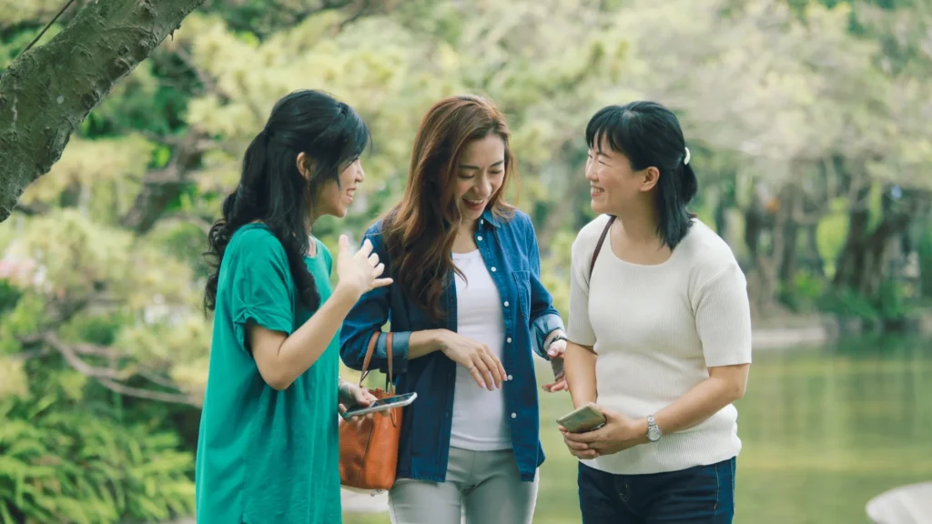 Three women chatting and glancing at a phone screen, engrossed in a lively conversation.