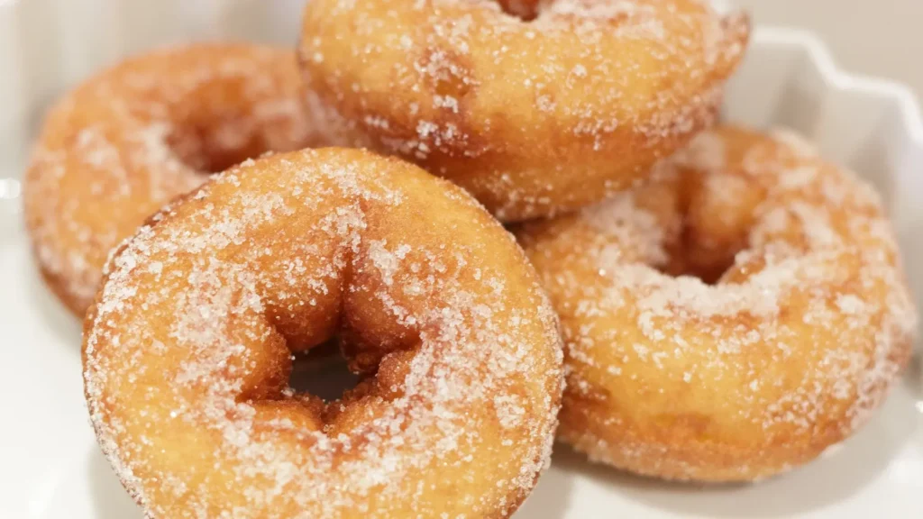 A plate of sugar-covered donuts on a white plate.