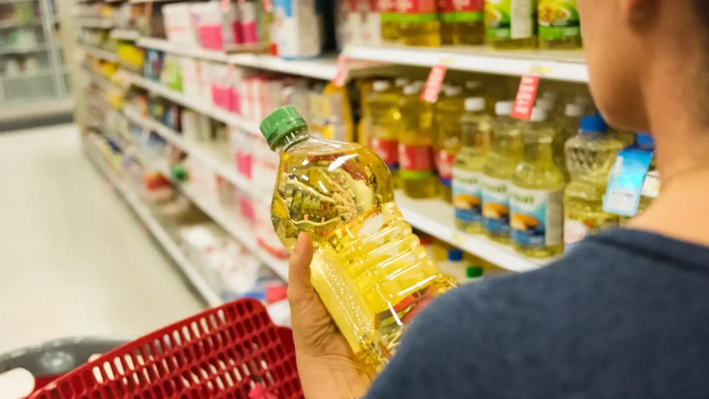 A woman holding a bottle of oil in a grocery store.
