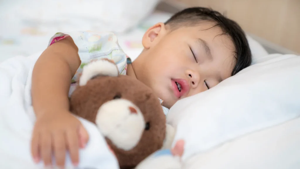A young child peacefully sleeping with a beloved teddy bear, finding comfort and solace in its presence.