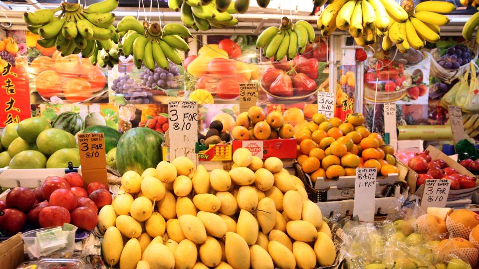 A colorful fruit stand displaying a variety of fruits including bananas, apples, and other delicious options.