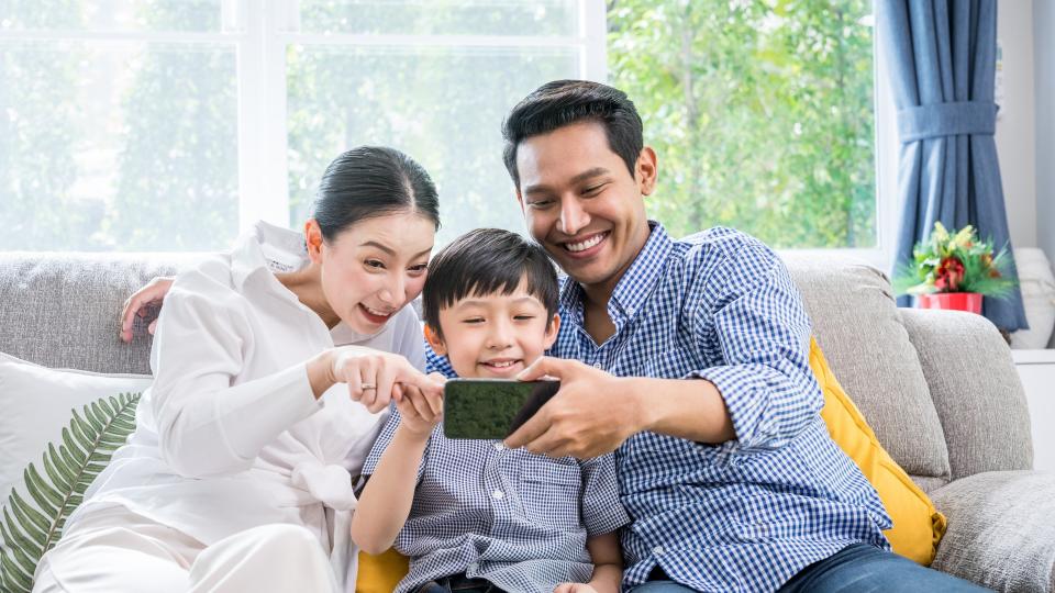A family happily using a smartphone together, sharing laughter and enjoying their time.