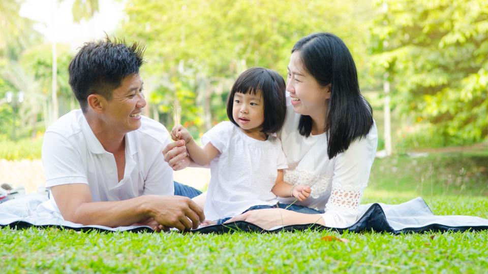 A family laughing and playing together in a sunny park, enjoying quality time outdoors.