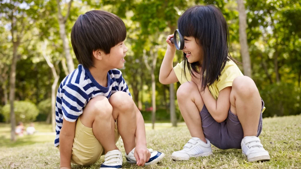 Two kids sitting on grass, gazing at something in the distance.