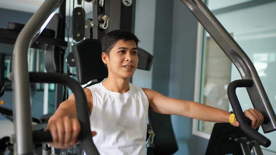 A man exercising on a gym machine, focusing on his fitness routine and improving his physical strength.