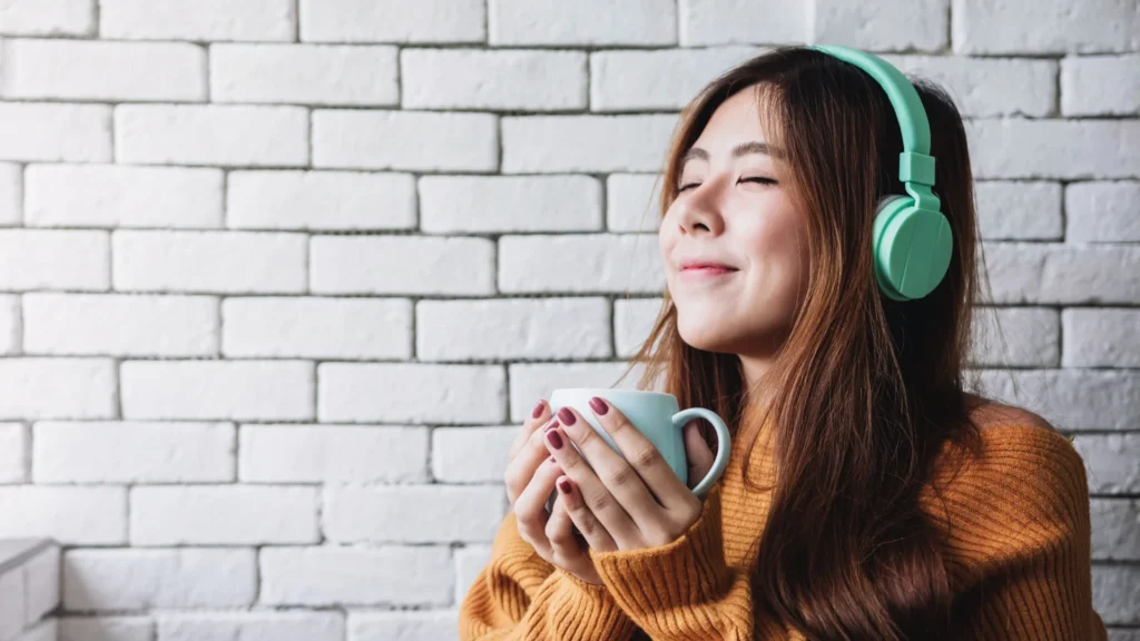 A woman enjoying music and sipping coffee.