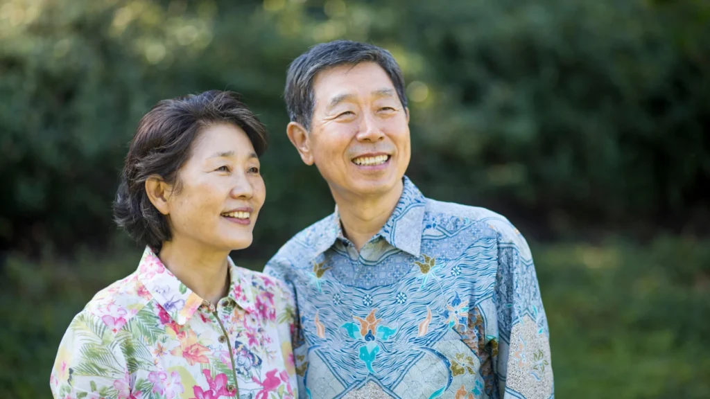 Elderly couple in matching floral shirts smiling together.