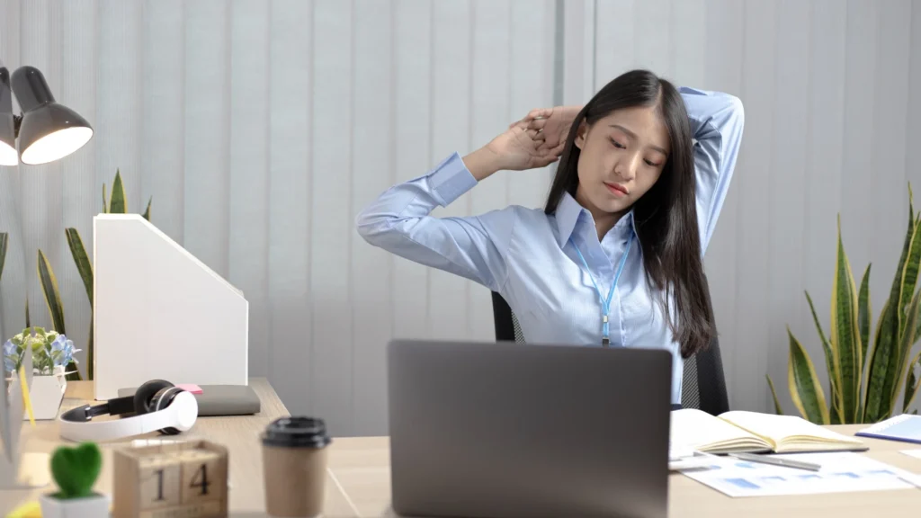 Stressed woman sitting at desk with head in hands.
